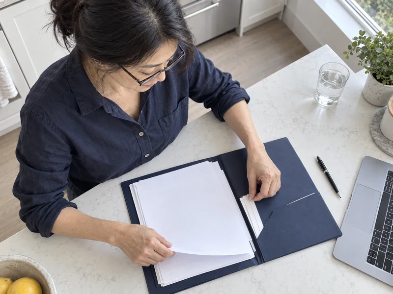 An overhead view of the same woman arranging documents in a navy folder